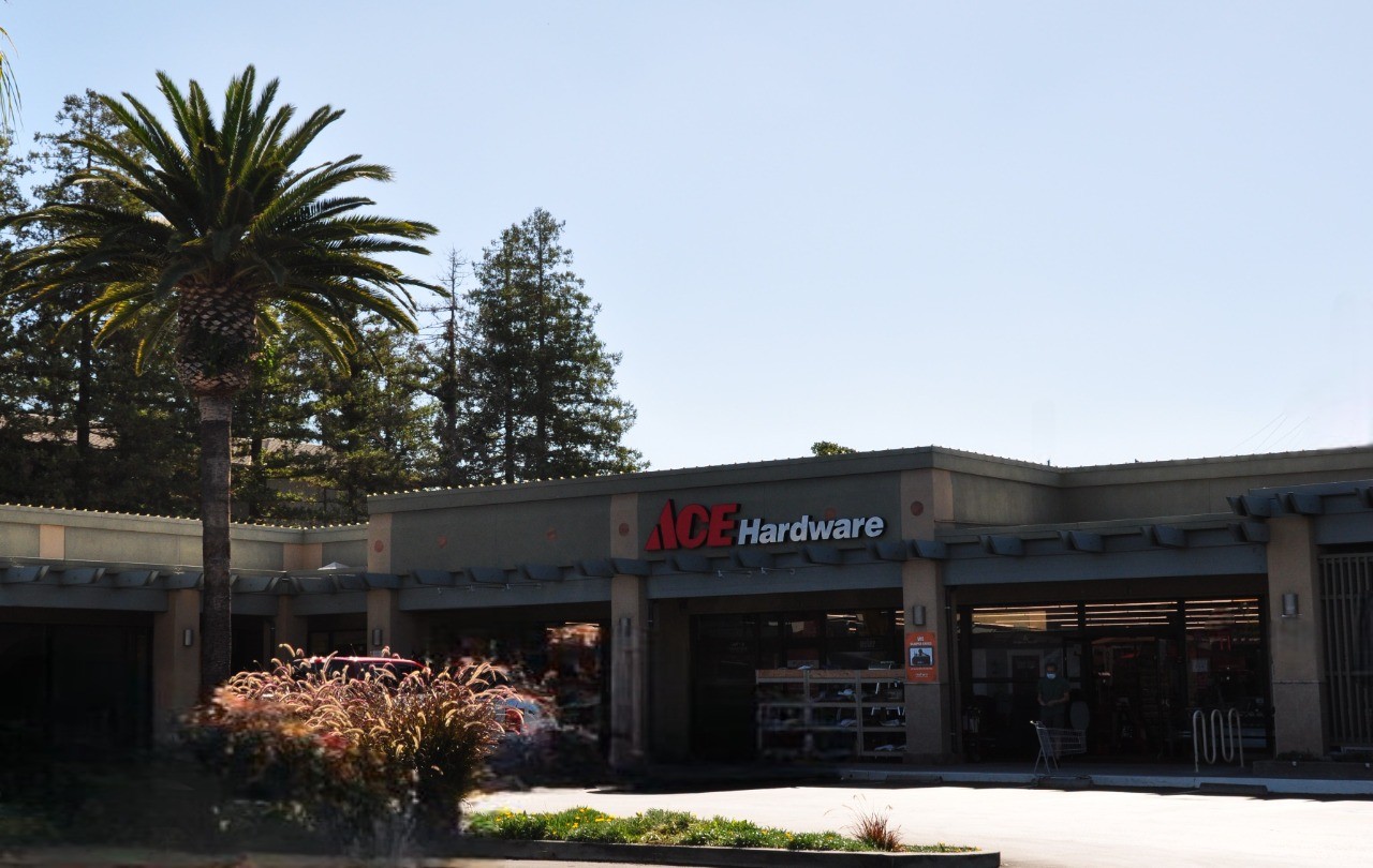 A parking lot view of the storefront signage at Ace Hardware.